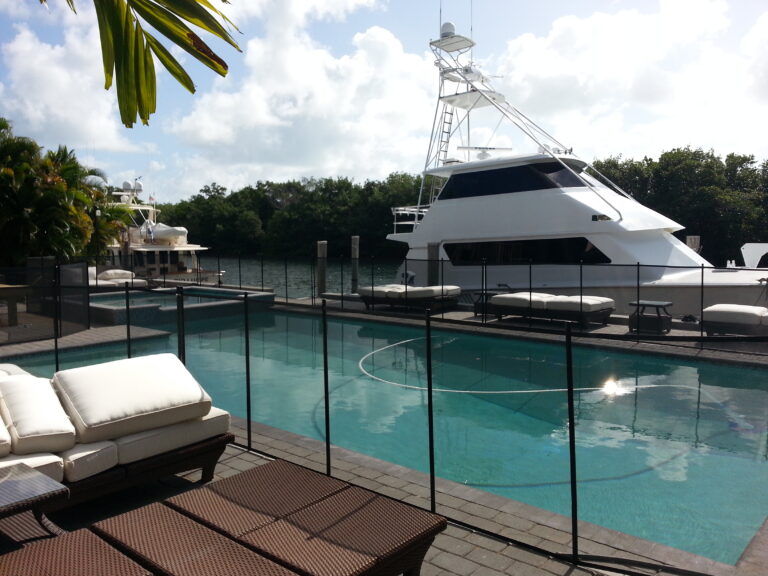 Black removable pool safety fence installed around a waterfront pool in Key Biscayne