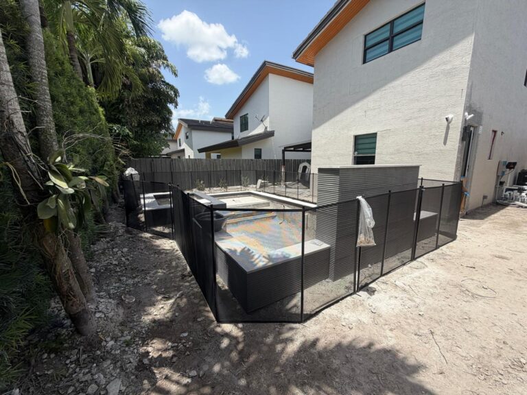 Black removable mesh pool fence installed using concrete footers around a residential pool