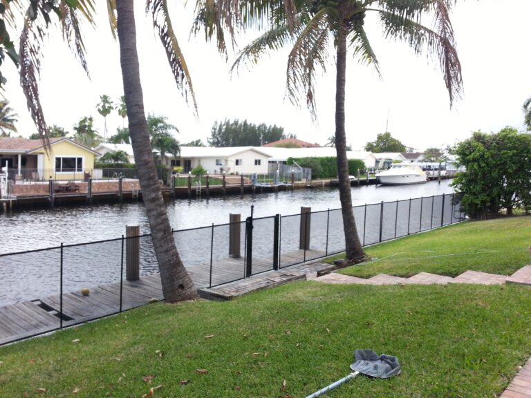 Removable mesh pool safety fence installed along a residential waterfront seawall
