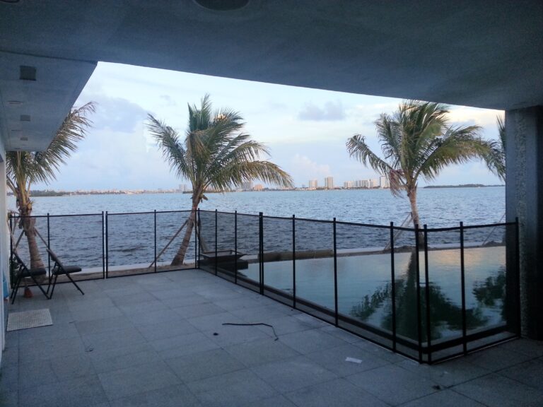 Black removable mesh pool safety fence installed at a waterfront home in Miami Beach