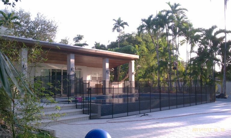 Black removable mesh pool fence installed across a pool deck with changes in elevation and steps