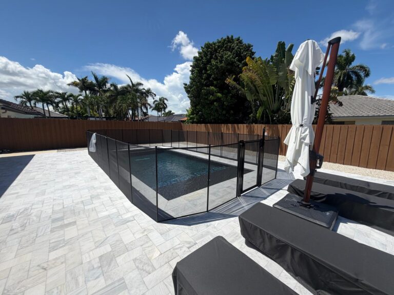 Black removable mesh pool safety fence installed in a custom layout around a residential pool patio