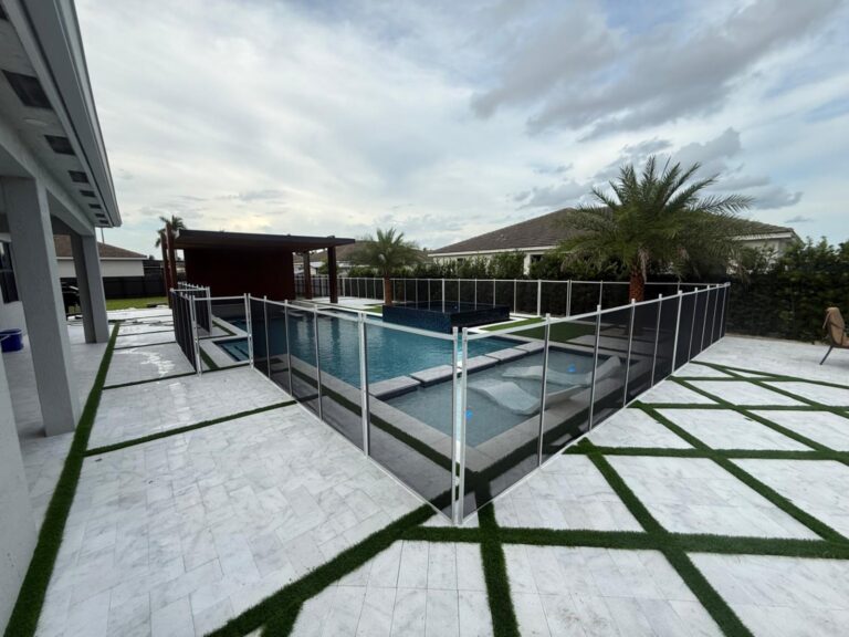 Black removable mesh pool safety fence with white posts around a modern pool and raised spa patio