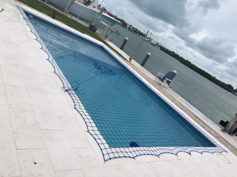 Blue pool safety net installed over a waterfront pool with a bay view