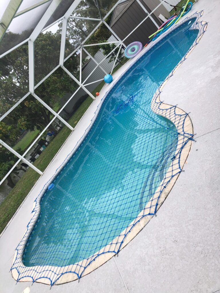 Blue pool safety net installed over a curved pool inside a screen enclosure