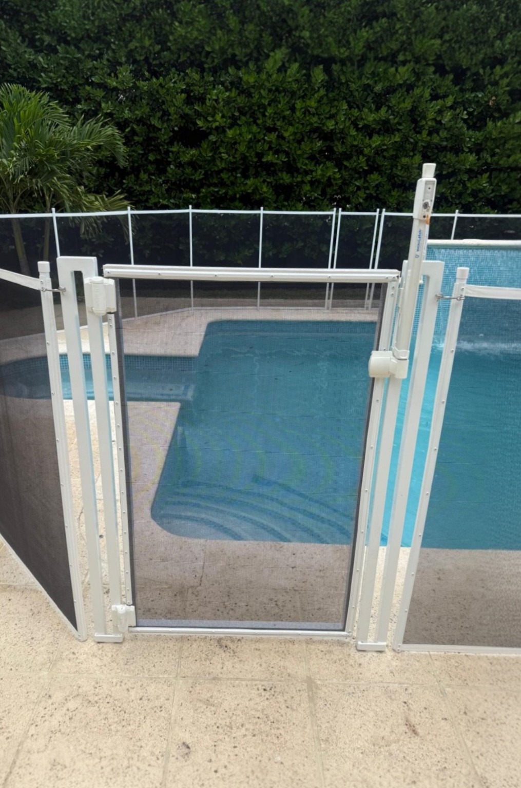White self-closing pool gate installed with a removable mesh fence